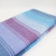 Tinizaray baby alpaca wool blanket – a folded, striped fabric features alternating pastel shades of blue, purple, and pink. It's placed on a plain white surface, showcasing its soft texture and subtle color transitions