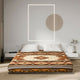 A bed is covered with a geometric patterned duvet in earthy tones, centered in a minimalist bedroom featuring a lit rectangular wall art piece and a round decorative element above.