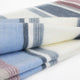 Pindo baby alpaca wool blanket – a folded blanket featuring a soft texture and pastel stripes in blue, gray, and pink, resting on a flat, white surface