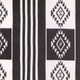 A fabric displays black and white geometric patterns, featuring diamond shapes and vertical stripes, creating a bold, symmetrical design. The texture appears soft, indicating it's likely a woven material.