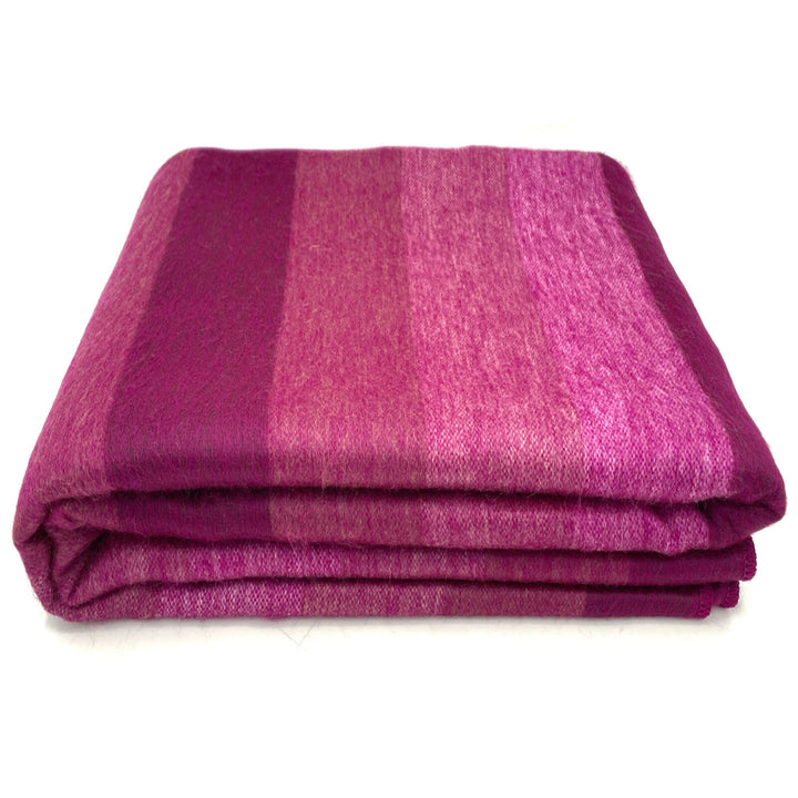 Chontamarca baby alpaca wool blanket – a folded, striped, pink-purple woolen blanket lies neatly stacked on a white background, showcasing its soft texture and gradient colors