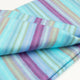 Tzacantza baby alpaca wool blanket – a folded, striped fabric features pastel colors, including blues, pinks, and purples, creating a soft, textured appearance. It rests on a plain, light background