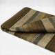 Atocha alpaca wool throw blanket – a folded woolen blanket with green, beige, and orange stripes lies on a flat surface, highlighting its texture and earthy color pattern against a neutral background