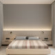 Zhumir baby alpaca wool blanket – a minimalist bedroom features a wooden bed with striped bedding, flanked by bedside wall lamps. The backdrop is a softly lit wooden panel, bordered by gray curtains