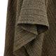 Brown and black houndstooth fabric drapes downward, showcasing its textured weave. The material appears folded, highlighting the intersecting woven pattern in a close-up view.
