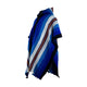 Wuachapa llama wool hooded poncho – poncho with blue, white, and brown stripes is hanging against a plain white background. The fabric appears textured, with fringed edges adding casual detail
