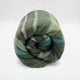 Jambue baby alpaca wool blanket – a rolled-up, striped woolen blanket with green, purple, and blue hues lies against a plain white background