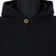 Achema llama wool hooded poncho – a dark, textured poncho features a single, round wooden button near the neck. The poncho is draped on a black mannequin in a neutral setting