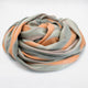 Tumbunuma baby alpaca wool blanket – a multicolored blanket coils into a loose circular shape, featuring soft hues of green, orange, and beige. It rests on a plain white background
