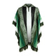A green hooded poncho features geometric patterns and fringe along the edges. It hangs in a symmetrical drape, set against a plain white background.