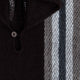 A knitted sweater features a button at the collar, with alternating dark and light vertical stripes, set against a textured, woolen background.