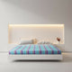 Tzacantza baby alpaca wool blanket – a bed with a blue-striped bedspread and pillows is centered against a modern, minimalist wall with integrated soft lighting and nightstands in a bright, minimalist bedroom