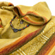 A yellow, patterned poncho lies folded, adorned with a rustic beaded necklace. The fabric displays intricate geometric designs, while the necklace features various textured beads.