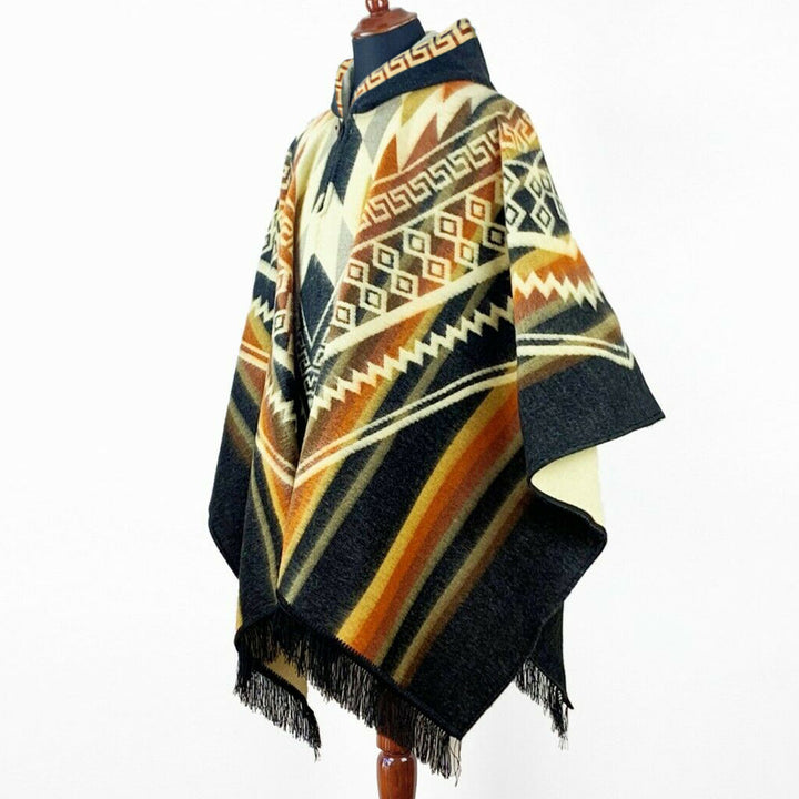 Shakai alpaca wool hooded poncho – a multicolored woven poncho featuring geometric patterns is displayed on a mannequin against a plain white background. The poncho has fringe details at the hem and a high collar