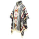 A woven poncho adorned with intricate geometric patterns in red, gray, and beige, hangs against a plain, white background. It features a high collar and fringed edges.