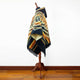 Shakai alpaca wool hooded poncho – a patterned poncho with geometric designs drapes over a wooden mannequin stand on a polished wooden floor, set against a plain white wall