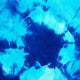 A vibrant blue tie-dye pattern radiates from a central dark blue area, with lighter blue and white sections. The textured fabric creates a dynamic, abstract design.