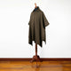 Zampu thick llama wool hooded poncho – a brown, plaid poncho drapes over a wooden mannequin stand, displayed against a plain white wall on a polished wooden floor