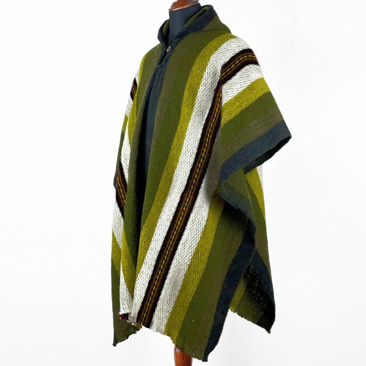 A striped poncho with varying shades of green, white, and black, is displayed on a mannequin against a plain white background.
