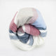 Pindo baby alpaca wool blanket – a soft, multicolored blanket featuring red, blue, gray, and white hues is neatly rolled against a plain white background