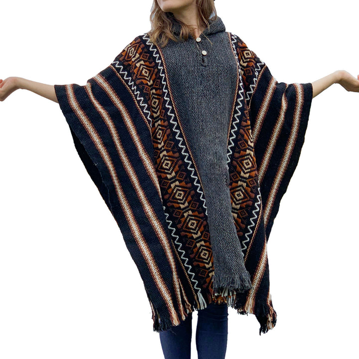 A person wears a multicolored poncho with geometric patterns, holding arms outstretched. The poncho features striped and diamond designs, and the person stands against a plain white background.